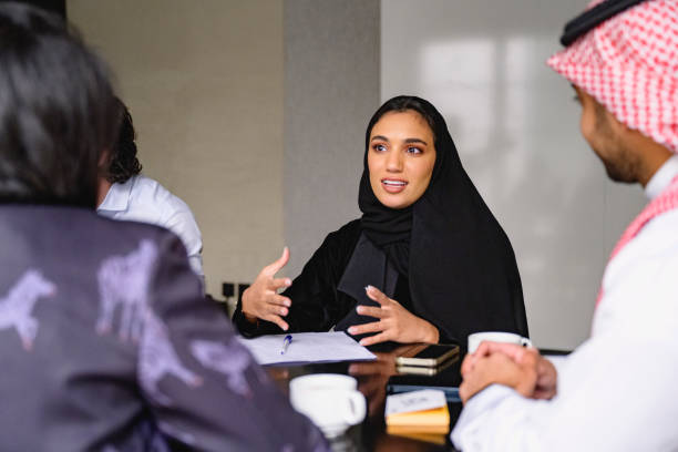 **"Middle Eastern businesswoman in a black abaya leading a discussion in a professional meeting with colleagues."**